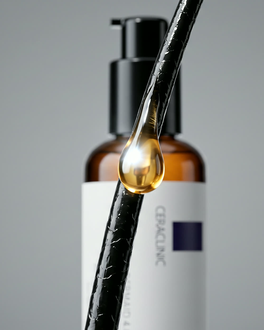 A drop of Ampoule Oil sliding down a strand of hair
